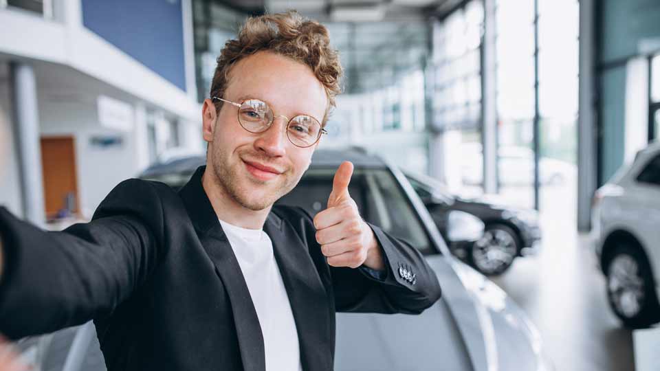 Ein Mann zeigt den Daumen hoch im Autohaus und steht für schnell und unkompliziertes Auto verkaufen