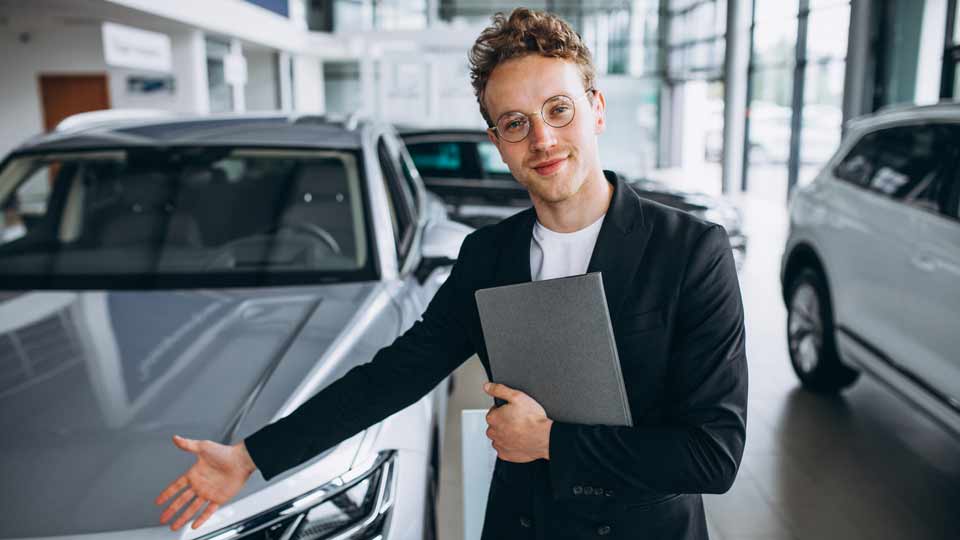 Ein Verkäufer zeigt auf ein Auto und erklärt dem Kunden die Konditionen beim Auto verkaufen Karlsbad